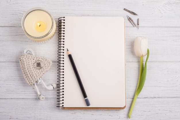 Open notebook, pencil, candle, earpods and tulip