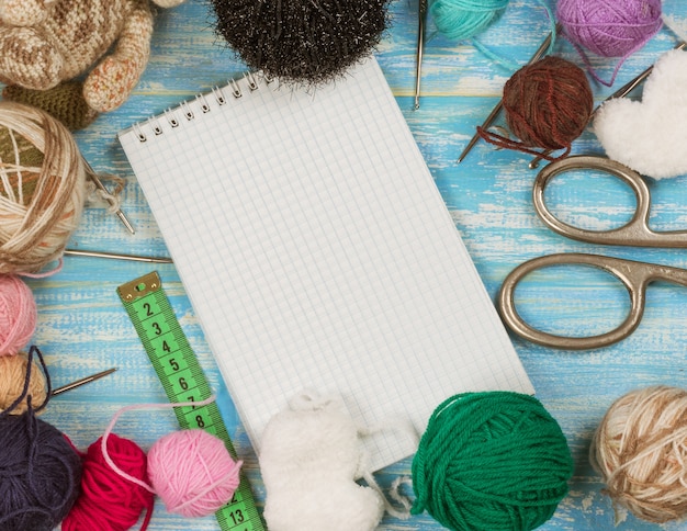 Open the notebook and set for needlework on a blue wooden table.