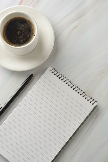 Open notebook with cup of coffee on marble desk. Workplace, work table. Top view.