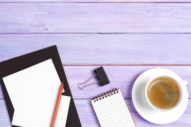 Open notebook with cup of coffee on wooden desk