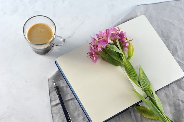 ユリの花とブラックコーヒーでノートブックを開く