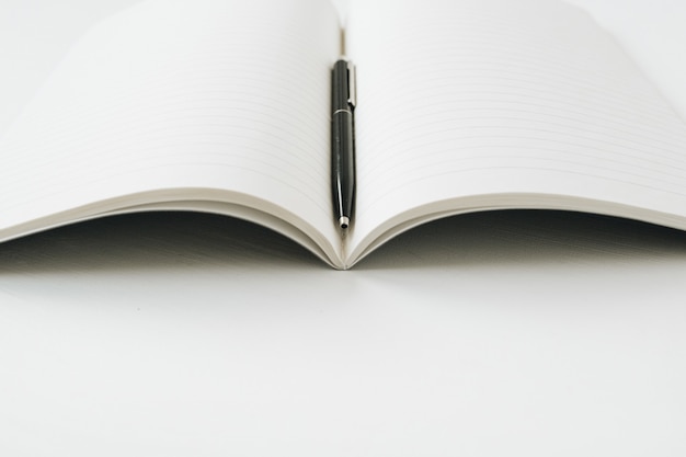 Open notebook with pen on white surface