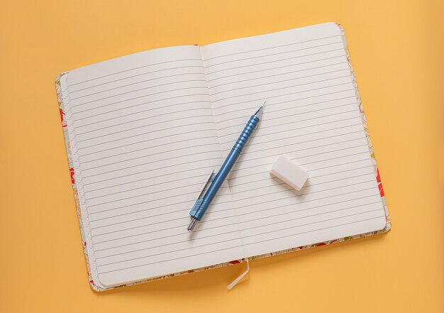 An open notebook with a pencil and eraser To convey ideas on a blank page. on a yellow background