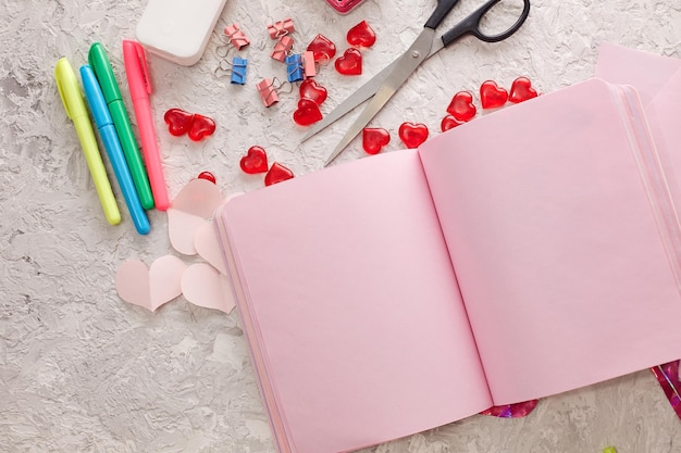 An open notebook with pink paper among the stationery