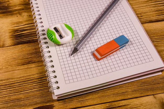 Open notepad and different stationeries on a wooden table