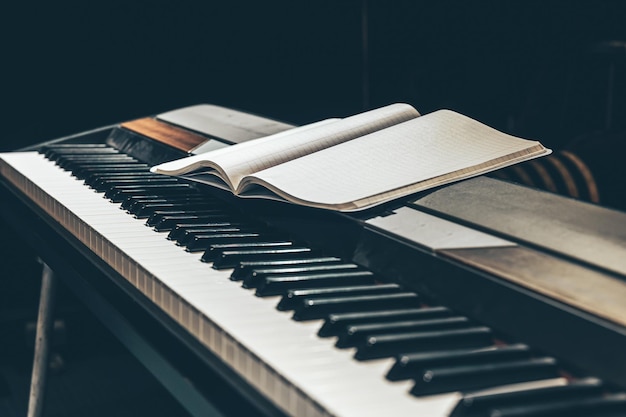 Open notepad on piano keys in the dark close up