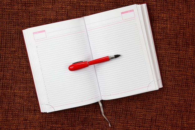 Open notepad and red pen closeup