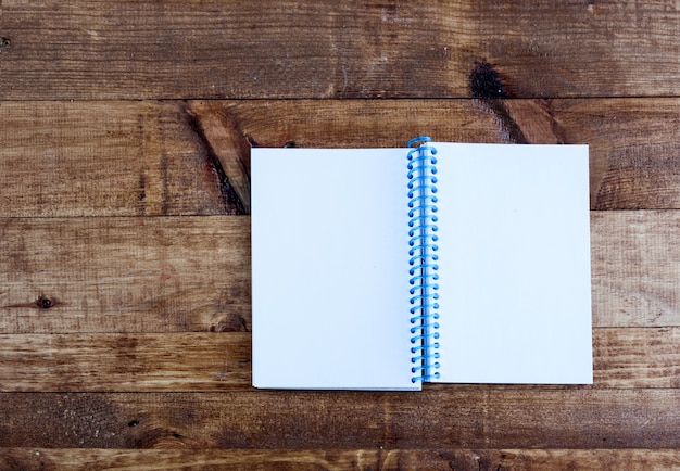 Open notepad with empty pages laying on a wooden table