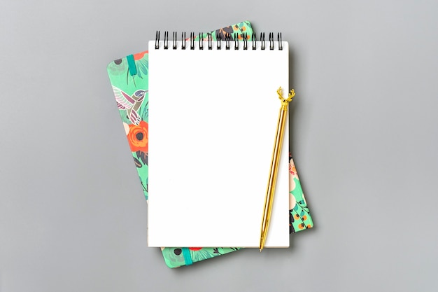 Open notepad with golden pen and spiral notebook on table