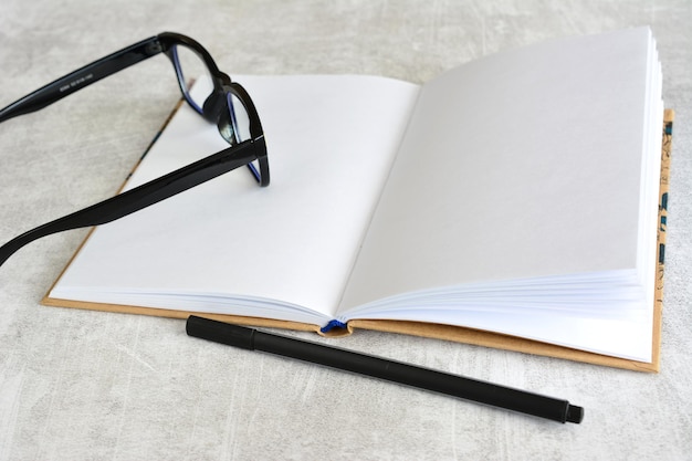 open notepad with white pages and pair of glasses and a pen