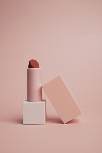Open nude lipstick in a case on pink background