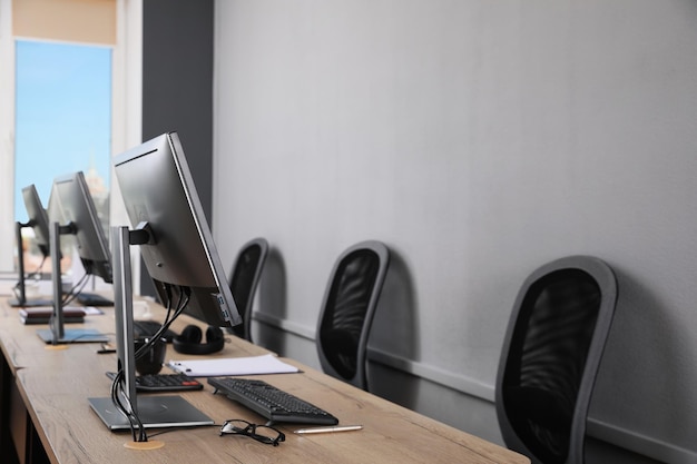 Open office interior Modern workplaces with computers near light grey wall