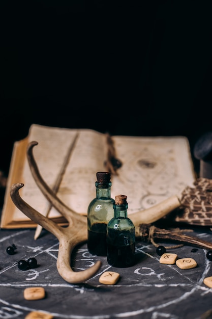 open old book with magic spells, runes, black candles on witch table. occult, esoteric, divination and wicca concept. halloween scene