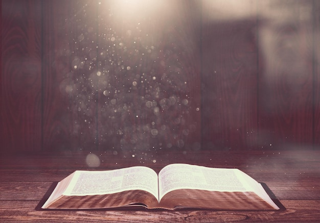 Open old book on wooden table.