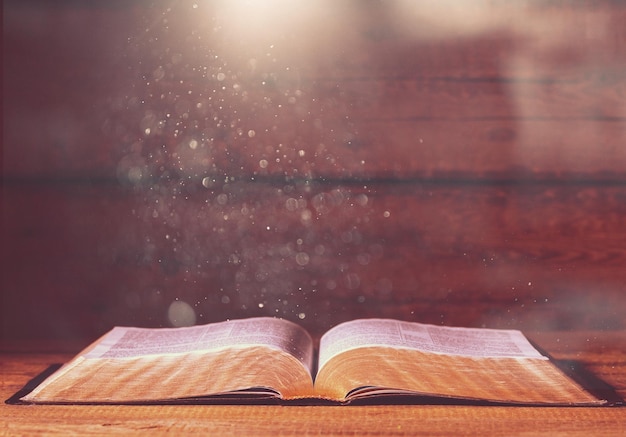 Open old book on wooden table.