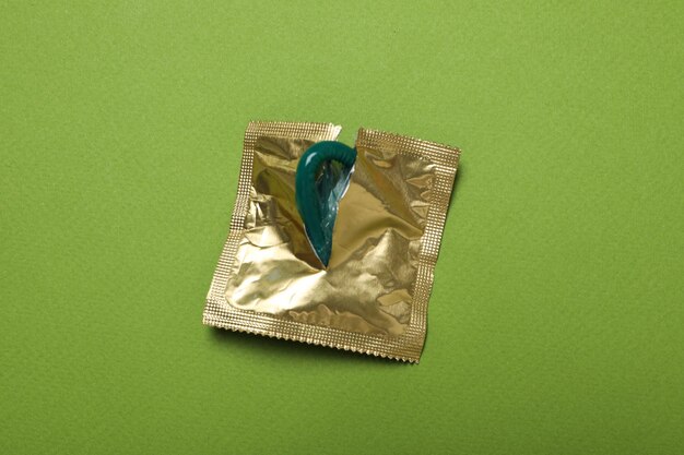 An open package with a condom on a green background