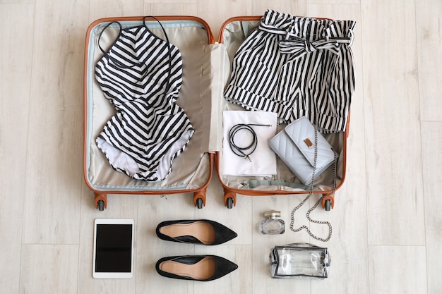 Open packed suitcase and accessories on wooden table