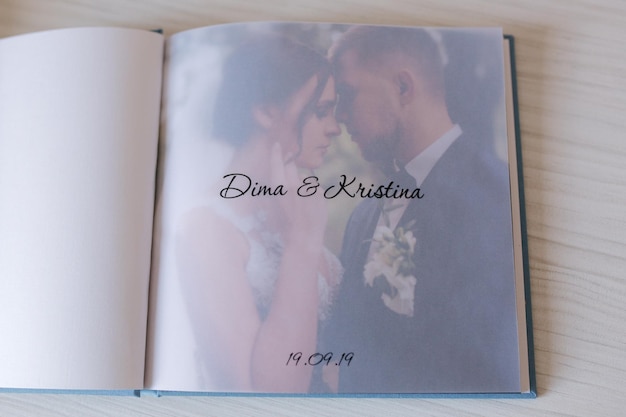 Open photobook with tracing paper with groom and bride on white wooden table