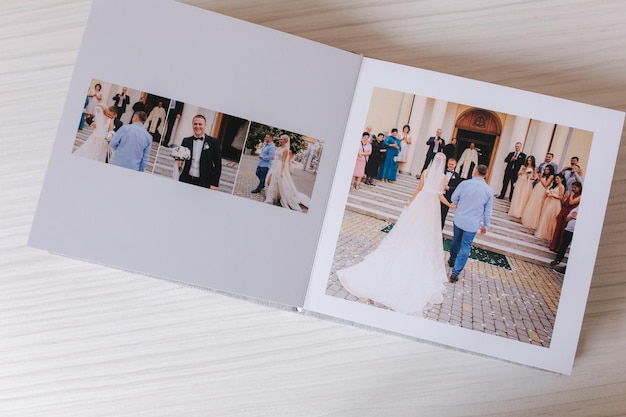 Foto fotolibro aperto con foto wrdding di una bella coppia su un tavolo di legno bianco