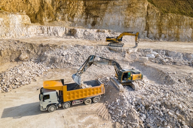 掘削機とダンプトラックによる建設砂岩材料の露天掘り。