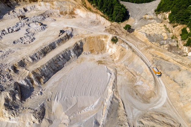 Open pit mining of construction sand stone materials with excavators and dump trucks.