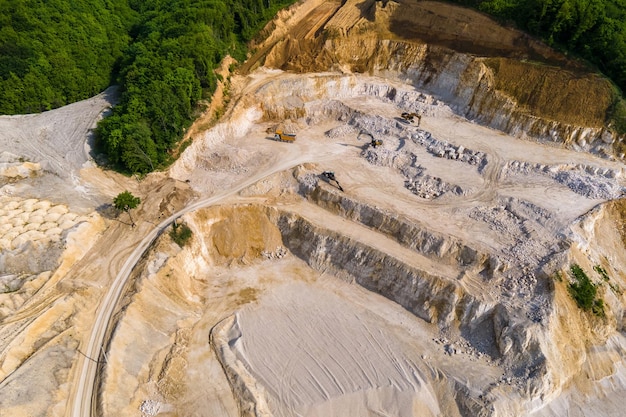 Open pit mining of construction sand stone materials with excavators and dump trucks.