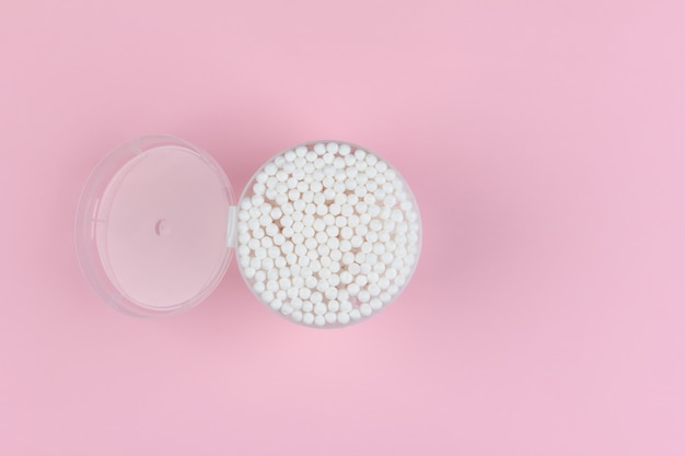 Open plastic box with cotton swabs on light pink 