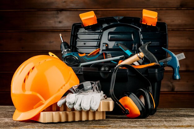 Open plastic tool kit box with construction safety helmet and various hand tools.