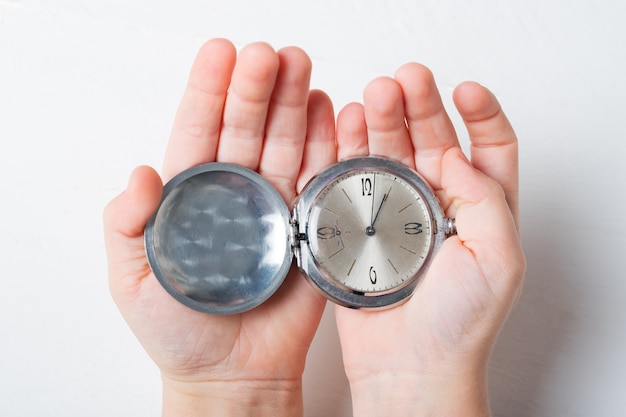 Open pocket watch in children's palms on a light