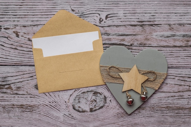 An open postal envelope and decoration in the form of a wooden heart on a wooden background. The concept of Valentine's Day. Flat lay.