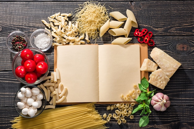 Open receptenboek en diverse verse ingrediënten voor het koken van pasta