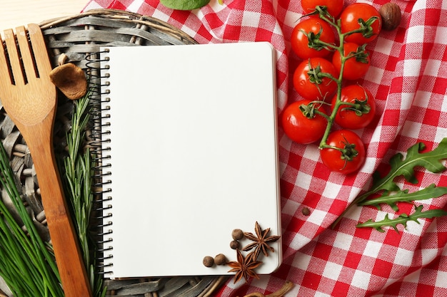 Open receptenboek met verse kruiden, tomaten en kruiden op houten achtergrond