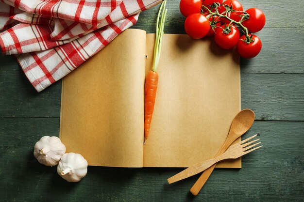 Open recipe book vegetables and spices on wooden background