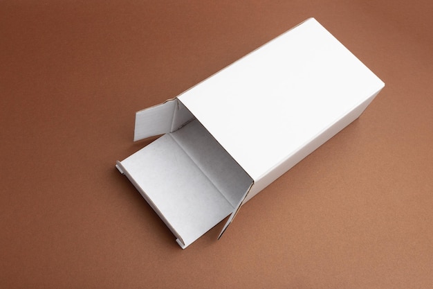 Open rectangular white cardboard box on brown background