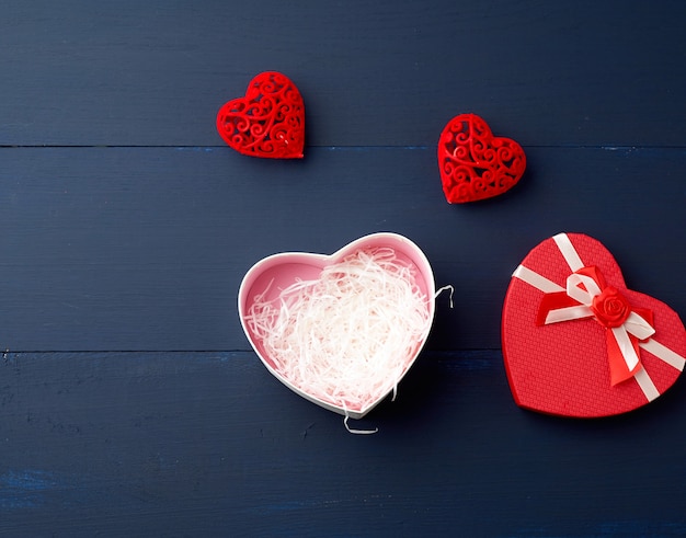 Open red heart-shaped gift box with a bow on a blue wooden 