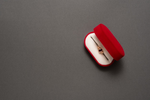 Open red jewelry box with jewelry on a black background.