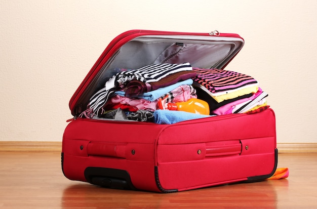 Open red suitcase with clothing in the room