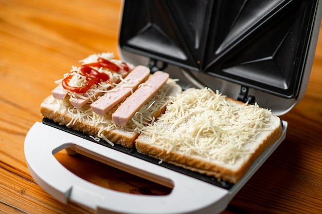 Open sandwich maker with cheese toast and sausages Sandwiching