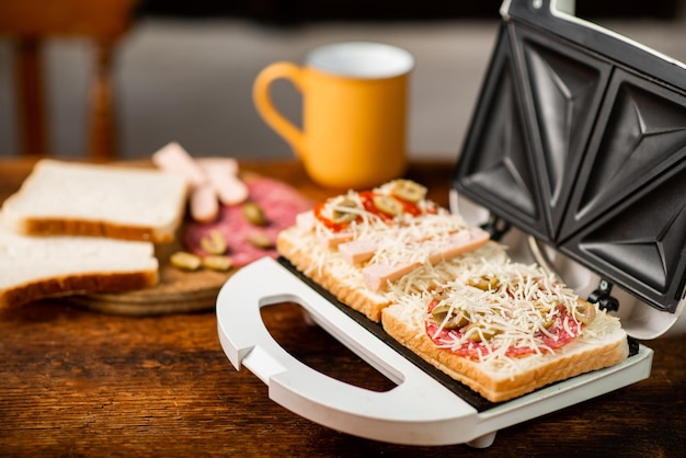 Open sandwich maker with cheese toast and sausages Sandwiching