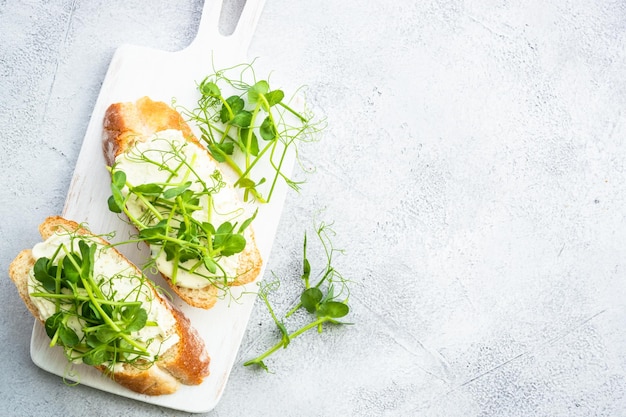 Open sandwich met roomkaas en microgroenten Gezond eten vegetarisch gerecht Plat op wit met kopieerruimte