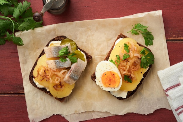 Photo open sandwich or smorrebrod with rye bread herring eggs caramelized onions parsley and cottage cheese on old wooden rustic table backgrounds danish or scandinavian traditional food snack lunch