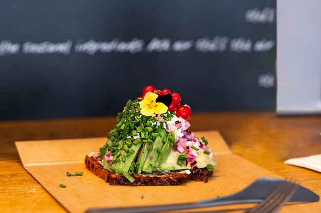 Open sandwich on a table in a cafe Danish traditional sandwich made of rye bread avocado red currants and sauce