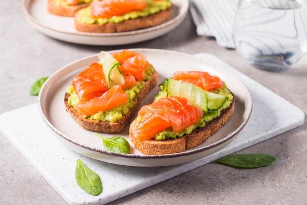 Open sandwich with smoked and salted salmon for healthy\
breakfast. trout and avocado on bruschetta t