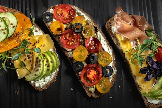 Open sandwiches met avocado kaasbaconcherry tomaat en olijfBovenaanzicht