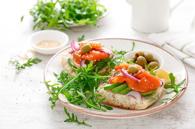 Open sandwiches with salted salmon avocado olives and arugula Breakfast