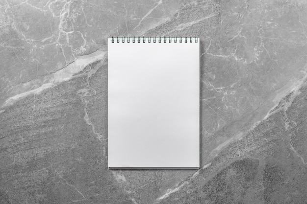 Open school notebook on marble table top view, notepad with blank page. flat lay of office concept