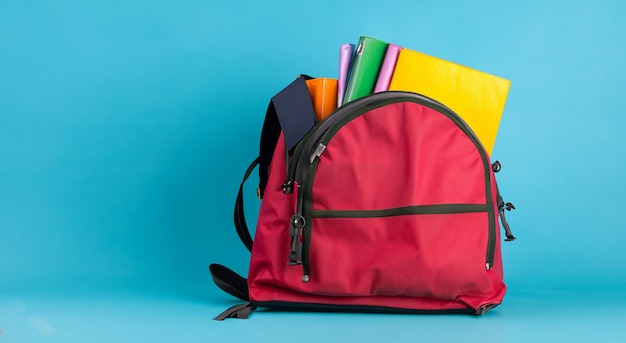 Open school red bag with books on blue background in high resolution