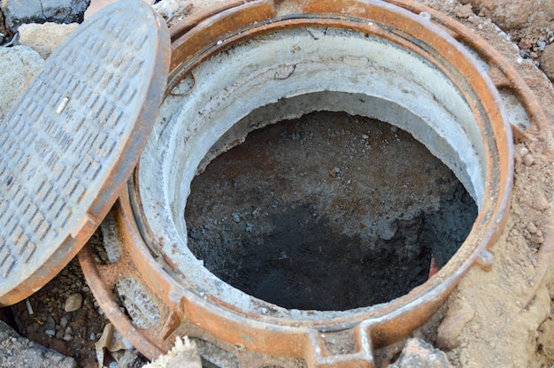 Open sewer on the street metal tunnel for water drainage creating a sewer passage rusty manhole