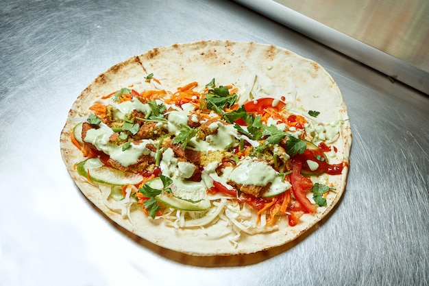 Open shawarma with falafel vegetables, cabbage, herbs and white pita sauce on a metal surface. Tasty street food kebab