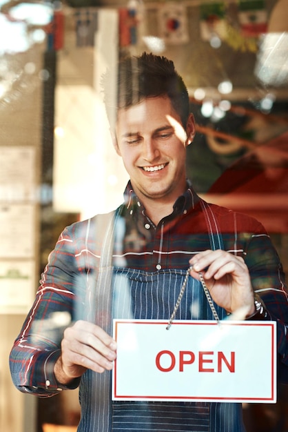 Photo open sign happy and man with startup success entrepreneur and service with restaurant coffee shop and smile male person employee and business owner with billboard opening store and welcome